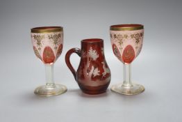 A pair of Bohemian overlaid glass goblets and a wheel engraved ruby glass jug (3) 15cm