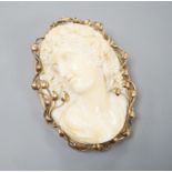 An early 20th century yellow metal mounted oval ivory cameo pendant brooch, carved with the bust