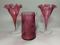 A pair of late Victorian cranberry glass frill vases, height 23cm, and a similar tapering jug