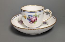 A Sevres coffee cup and saucer painted with floral bouquets under a dentil gilt and blue line