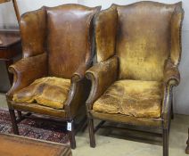 A pair of George III style tanned leather wing armchairs