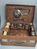A George V leather travelling toilet case, containing twenty one matched, mainly silver and