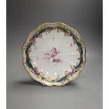 A Chelsea-Derby circular dish painted in puce with a cherub floating on a cloud by Richard Askew,