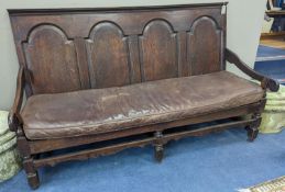 A mid 18th century panelled oak settle with leather squab seat, length 185cm, depth 77cm, height