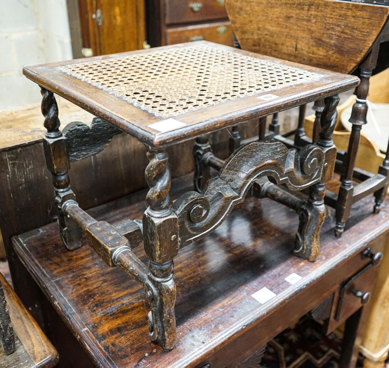 A 17th century style carved oak stool, with caned seat and H stretcher, width 47cm, depth 46cm,