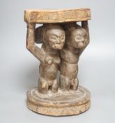 A Yoruba carved wood stool, modelled with male and female figures 27cm