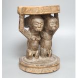 A Yoruba carved wood stool, modelled with male and female figures 27cm