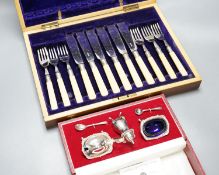 A cased modern silver three piece condiment set, a cased set of twelve Edwardian silver teaspoons,