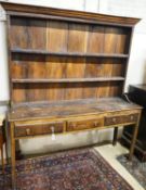 A George III oak dresser, with two shelf rack and three long drawers, on chamfered legs, width