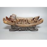 A Chinese horn carving of a junk boat, wood stand, 34cm