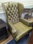 A George III style wing armchair upholstered in studded buttoned green leather, width 79cm, depth