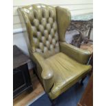 A George III style wing armchair upholstered in studded buttoned green leather, width 79cm, depth