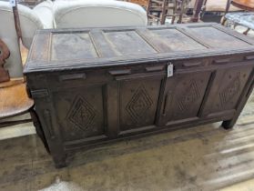 An early 18th century oak coffer, with four panel top and later carved and applied decoration,
