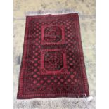 An Afghan red ground rug, 140 x 96cm