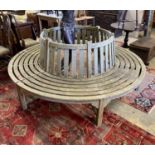 A weathered teak sectional circular garden tree seat, aperture approx. 106cm, seat diameter 220cm,