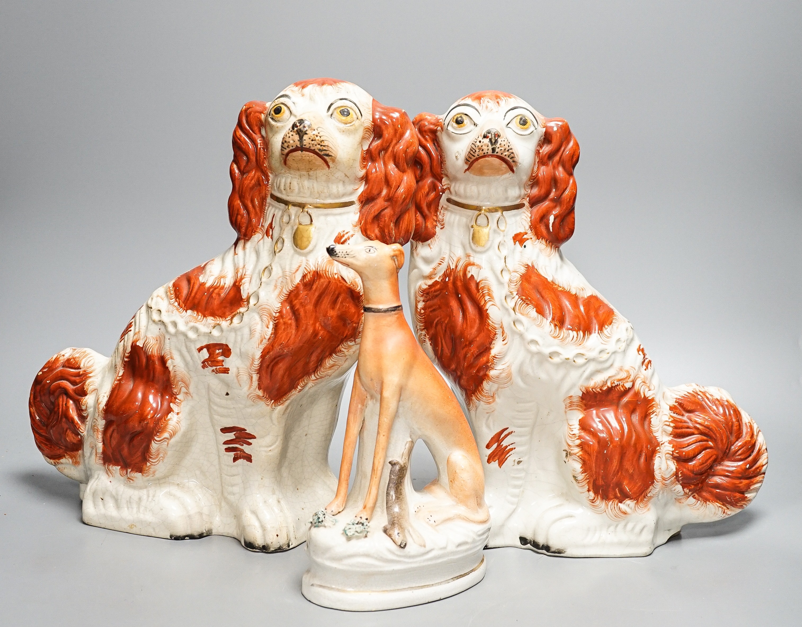 A pair of Victorian Staffordshire Spaniel chimney dogs and a greyhound, chimney dogs 31 cms high.