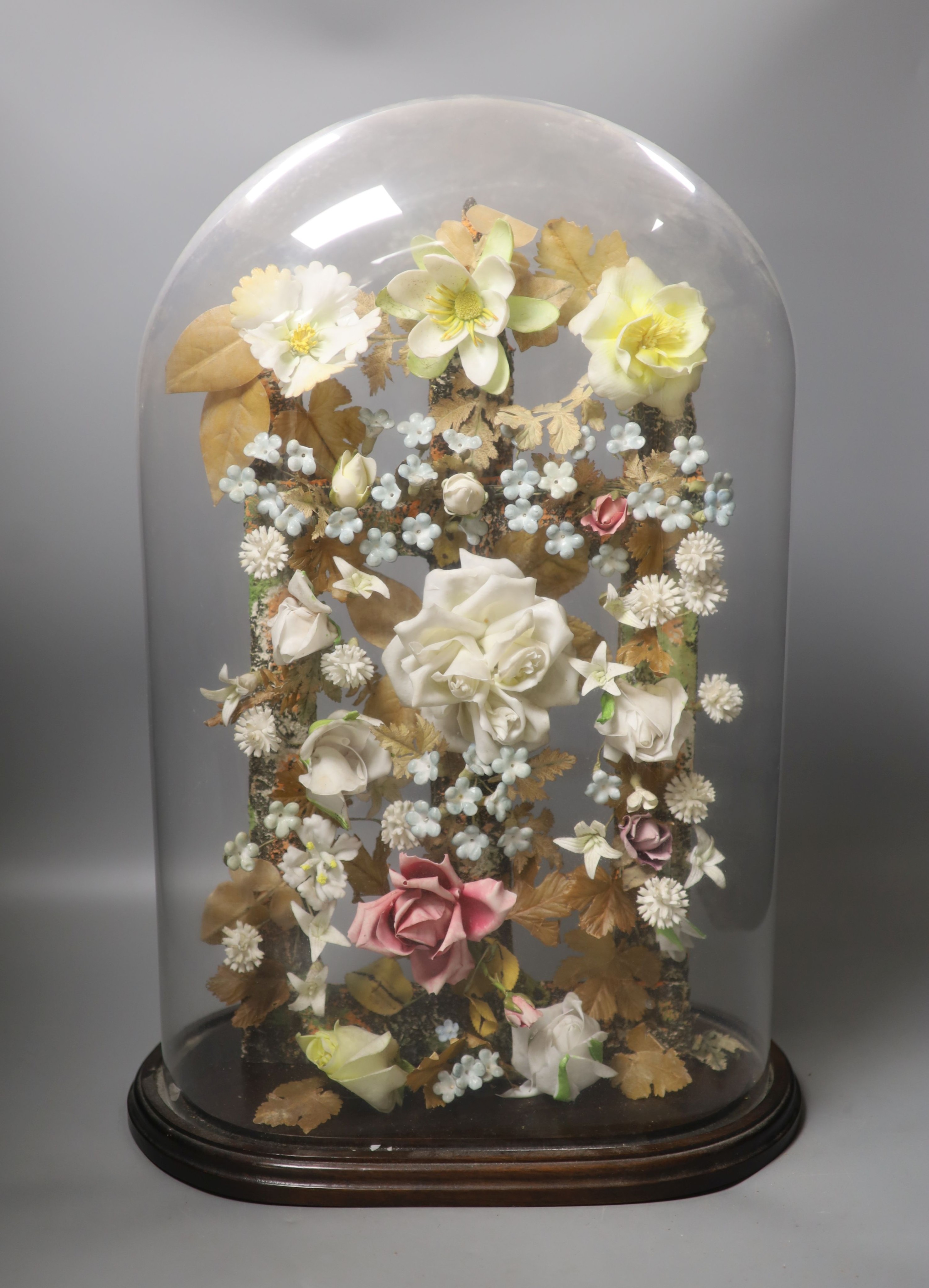 A late 19th century model of porcelain flowers under a glass dome 52cm total height