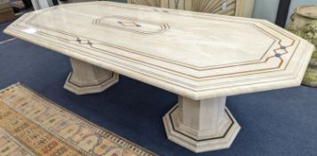 A Travertine marble dining table of elongated ocgtagonal form on twin octagonal column supports,