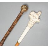 An early 20th century ivory ‘sphinx’ parasol handle, 84cm, together with another gold and iron