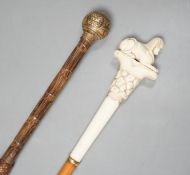 An early 20th century ivory ‘sphinx’ parasol handle, 84cm, together with another gold and iron