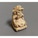 A late 19th/early 20th century carving of a girl seated on a cushion, 5 cms high