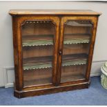 A Victorian walnut veneered bookcase with twin panelled glazed doors, length 126cm, depth 33cm,