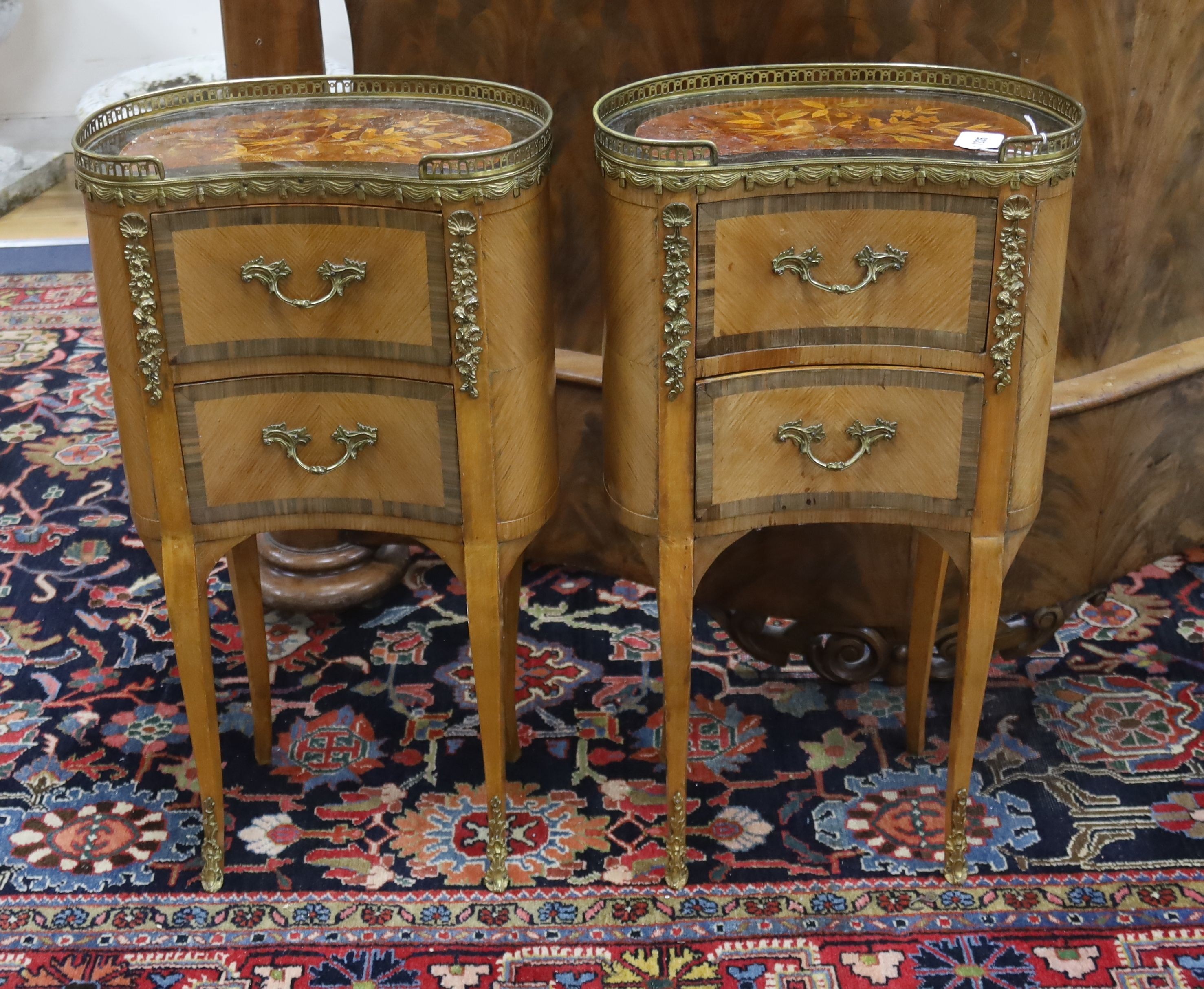 A pair of French marquetry inlaid gilt metal mounted kidney shaped two drawer bedside cabinets,