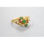 A modern yellow metal, emerald, ruby and seed pearl cluster set crossover ring, size L, gross weight
