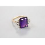 A yellow metal and single stone emerald cut amethyst dress ring, with trapeze and round cut