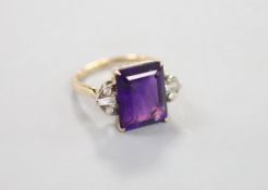 A yellow metal and single stone emerald cut amethyst dress ring, with trapeze and round cut