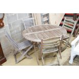 A weathered teak circular folding garden table, diameter 116cm and two pairs of folding chairs