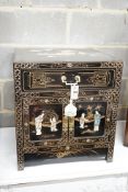 A Chinese black-lacquered brass-mounted small two-door cabinet, the door panels decorated with