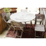 A weathered teak circular folding garden table and five folding chairs