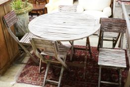 A weathered teak circular folding garden table and five folding chairs