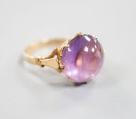 An early 20th century yellow metal and button shaped cabochon amethyst set ring, size R/S, gross