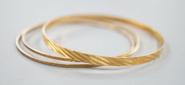 A 14k yellow metal bangle and two other brushed yellow metal bangles stamped 'K14', gross 12 grams.
