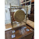 An Edwardian brass dinner gong with striker, width 50cm, height 84cm