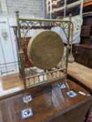 An Edwardian brass dinner gong with striker, width 50cm, height 84cm