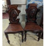 A pair of Victorian carved mahogany hall chairs, a.f.