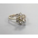 An 18ct and seven stone diamond set flower head cluster ring, size F/G, gross weight 3.2 grams.