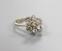 An 18ct and seven stone diamond set flower head cluster ring, size F/G, gross weight 3.2 grams.