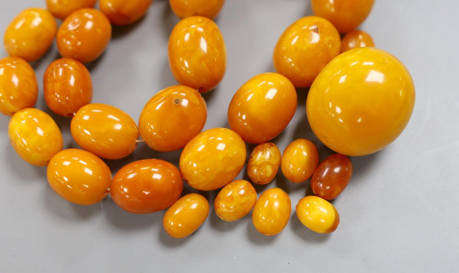 A single strand graduated oval amber bead necklace, 43cm, gross weight 51 grams and a few loose