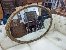 An early 20th century carved gilt oval wall mirror, width 110cm, height 80cm