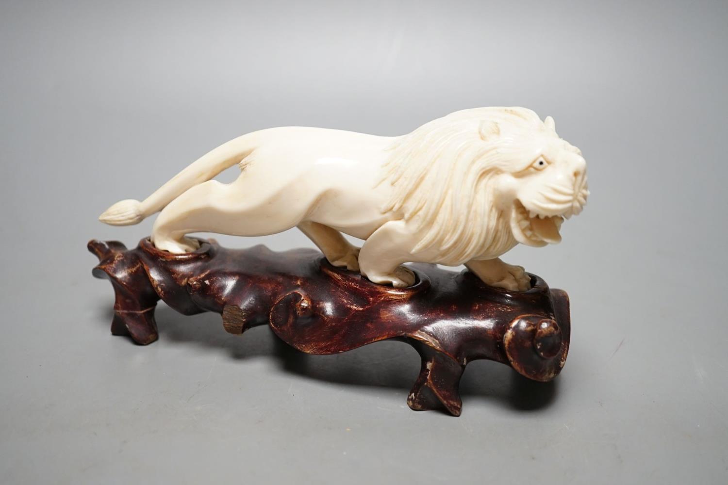 A Chinese ivory figure of a lion, on wooden stand, early 20th century, stand 20 cms wide. - Image 2 of 2