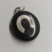 A late Victorian white metal and black enamelled oval mourning locket, with horseshoe applique and