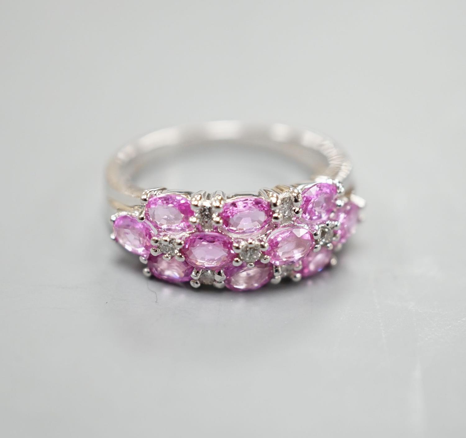 A modern 14k white metal, pink sapphire and diamond cluster set half hoop dress ring, size O,