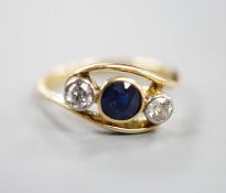 A modern 18ct gold, single stone diamond and two sapphire set crossover ring, size K, gross 3.2