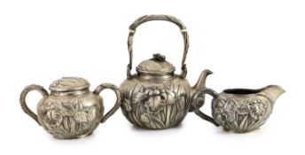 A Japanese Meiji period three piece silver tea set,embossed with irises, (a.f.), Jungin mark, teapot