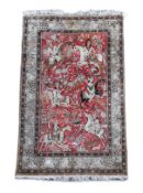 An early 20th century Tabriz pictorial red ground rug, woven with hunters on horseback,the border