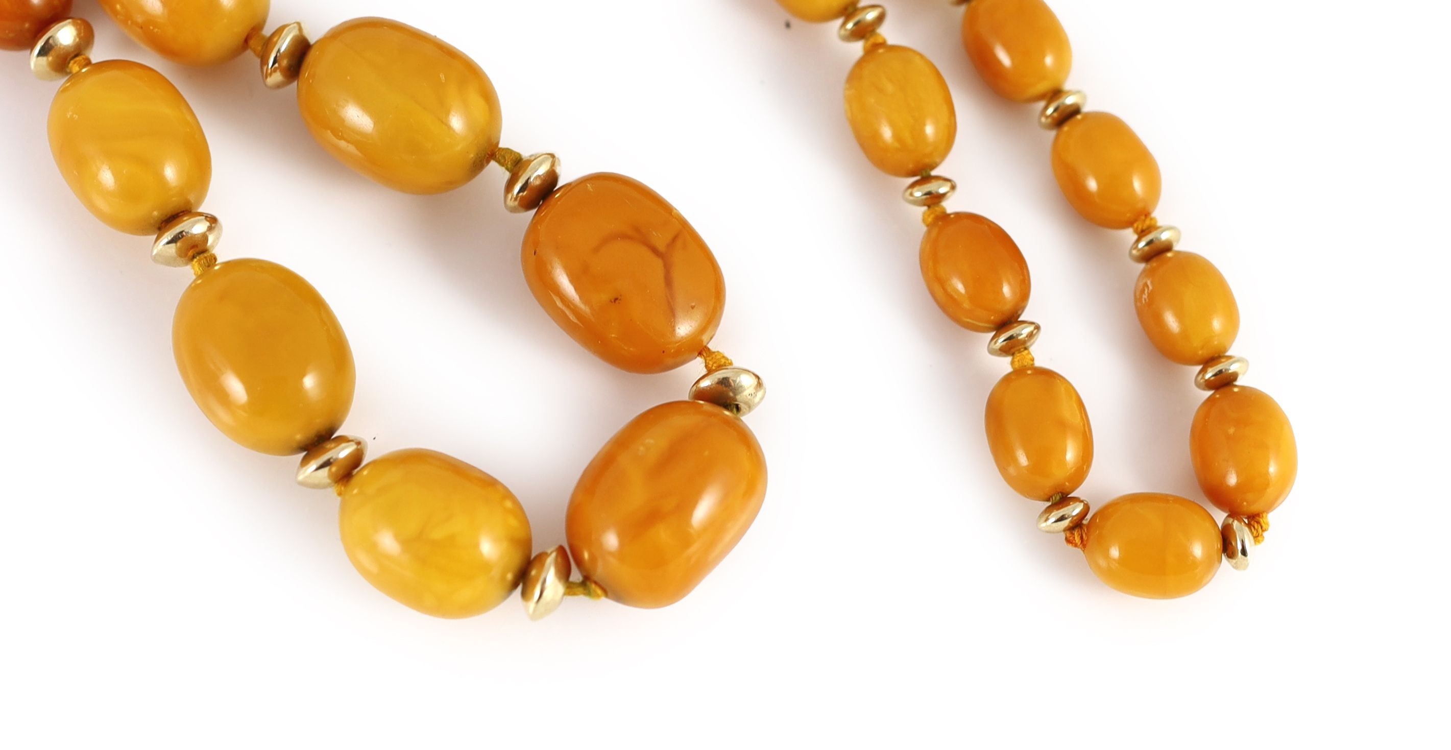 A single strand graduated oval amber bead necklace, with gilt metal spacers, 80cm, gross weight 92